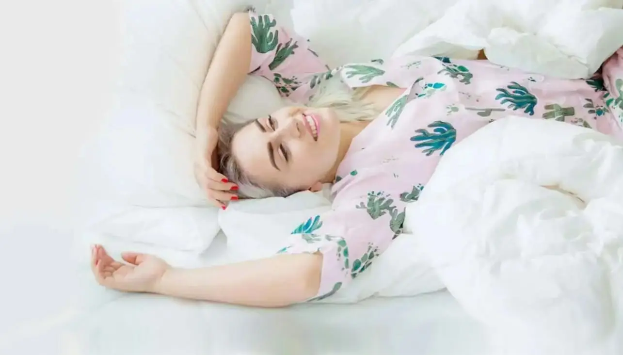A woman lies comfortably on a luxurious down duvet